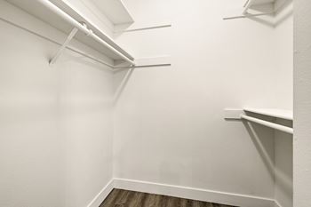 A white closet with a wooden floor and three shelves.